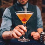 Bartender Serving Manhattan Cocktail In Martini Glass