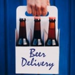 Man's Hand holding a six pack of brown beer bottles