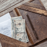 cash tip left in a restaurant check on a wooden table