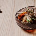 Mujo agedashi dish on a wooden table with chopsticks