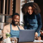 woman smiling with man as they both look at computer