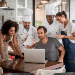 restaurant employees gathered around a computer smiling.